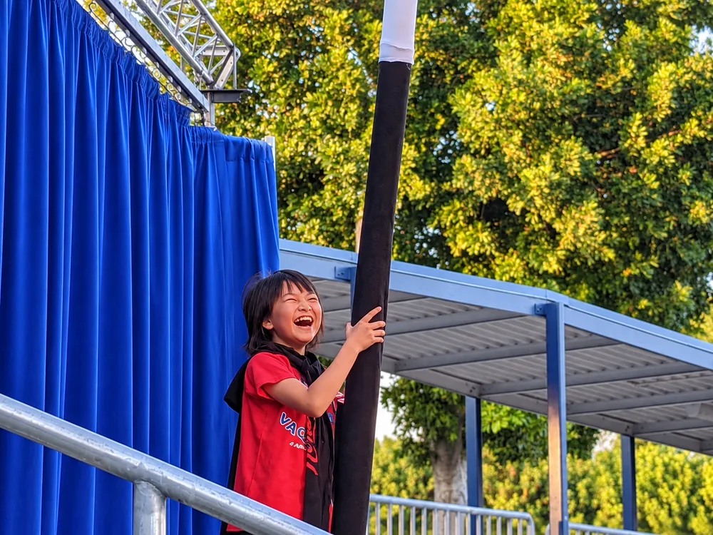 Elementary student laughing while holding an enormous magic wand during The Patchwork Quilt routine