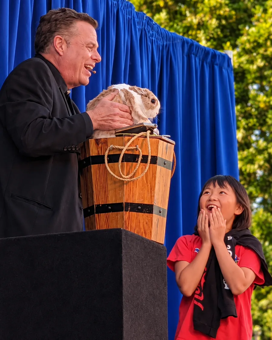 Brock Edwards revealing a live rabbit to a delighted student volunteer during The Velveteen Rabbit routine